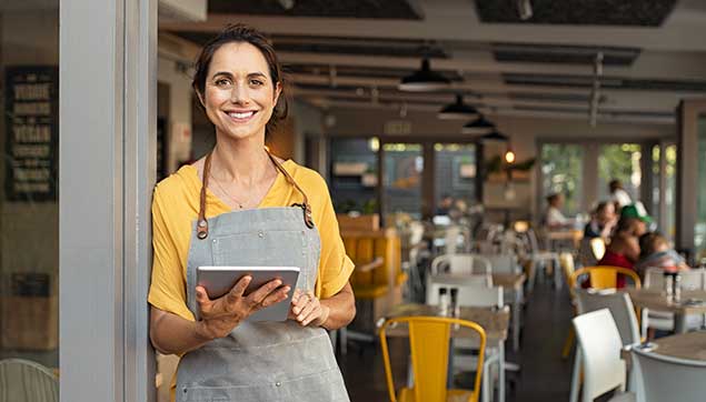 Portrait Of Happy Woman Standing At Doorway Of Her Store